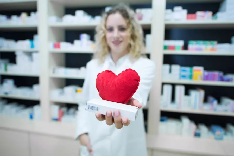 Female Pharmacist holding pill box and heart